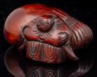 Japanese Netsuke: Fine 19th Century Boxwood Carving of a Man Resting Against a Large, Tied Bundle or Bag